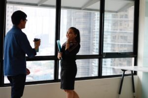 male employee and female employee talking in front of a window